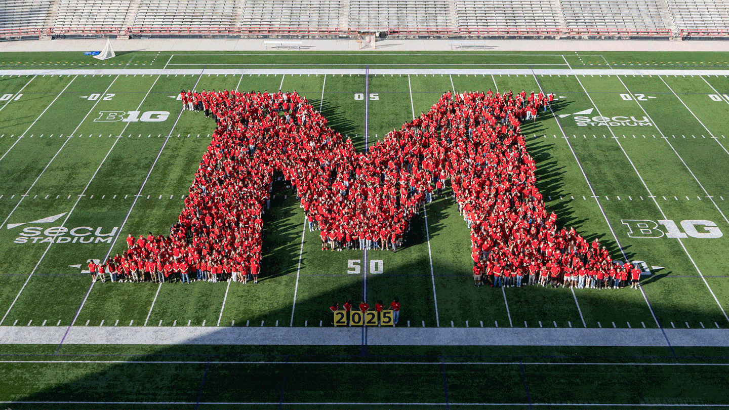 gif of students in red shirts forming M on football field