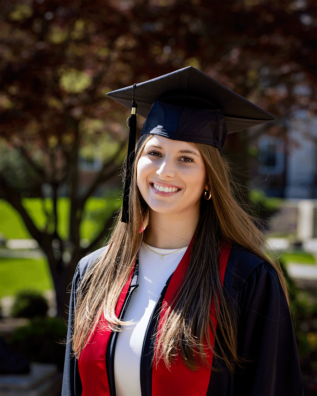 A student in graduation cap and gown shown with sunlight on and off her face in a moving gif